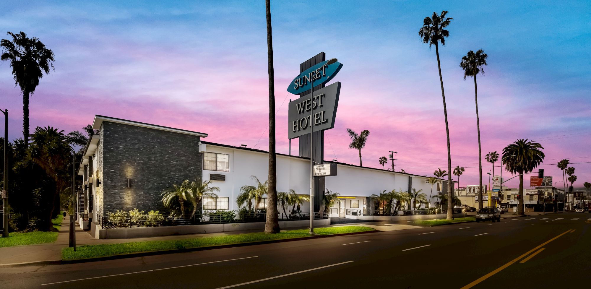 A modern motel with a "Sunset West Hotel" sign, palm trees, and a pink and blue sky in the background.