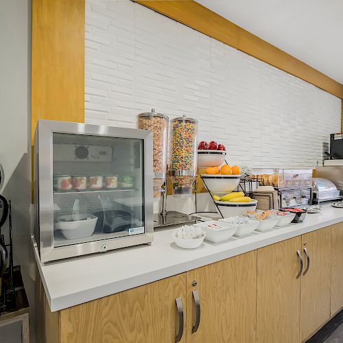 A breakfast station with cereal dispensers, a food warmer with yogurt, fruit, and a drink station with coffee dispensers and juice machine.