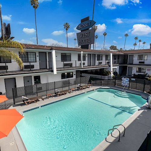 The image shows a hotel courtyard with a swimming pool surrounded by lounge chairs, palm trees, and an orange umbrella, with a "Sunset West Hotel" sign.